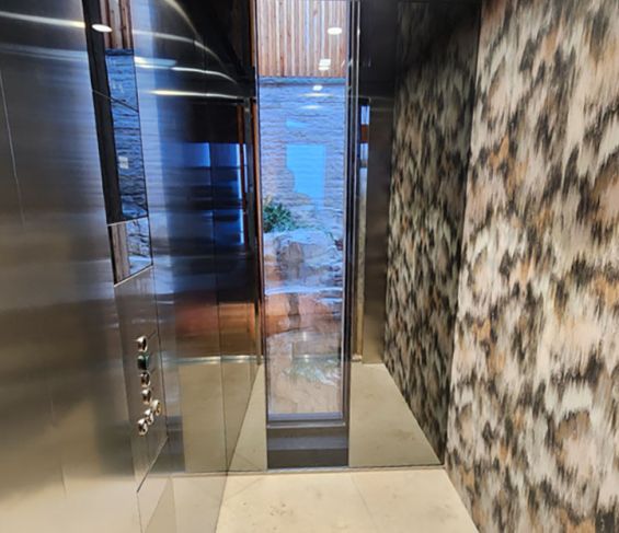 Geöffnete Aufzugskabine mit gemusterter Wand im Projekt Bellevue in Aurach.